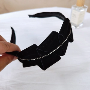 Detail of black velvet headband featuring a side bow with sparkling rhinestone edges