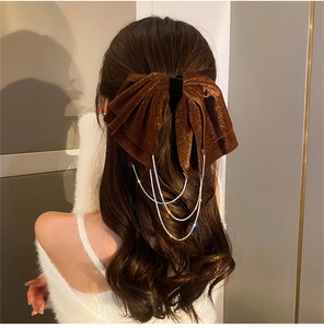 Detail of velvet bow hair clip with sparkling rhinestone tassels on wavy hair