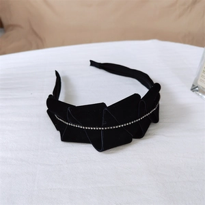 Detailed macro view of black velvet headband featuring layered bow and sparkling rhinestone chain
