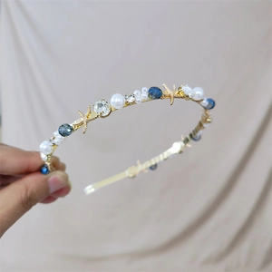 Elegant gold headband featuring white pearls, blue crystals, and sea star charms