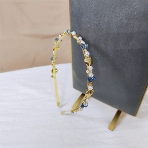 Detail of gold seashell headband featuring white pearls and blue crystal beads on display