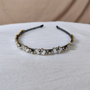 Détail du serre-tête vintage orné de cristaux blancs et perles sur monture foncée