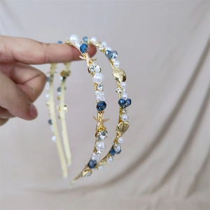 Detail of seashell headband featuring blue crystals and pearls on a gold frame