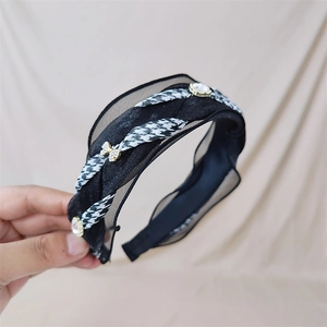 Detailed shot of houndstooth plaid headband with sheer ruffle edges and rhinestone bow