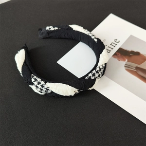 Classic black and white houndstooth cross braided headband on a minimalist backdrop