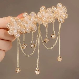 Detailed macro view of beaded flower hair clip with champagne tassels and amber crystal stones
