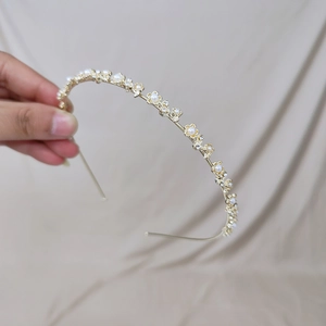 Détail du serre-tête doré orné de perles œil de chat et de fleurs en cristal