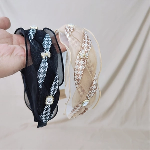 Detailed close-up of houndstooth headband with sparkling rhinestone bow and crystal