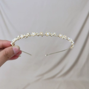 Gros plan d'un serre-tête doré orné de perles blanches et de strass scintillants