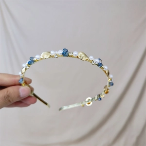 Detailed close-up of a gold headband featuring blue crystal drops and white pearls