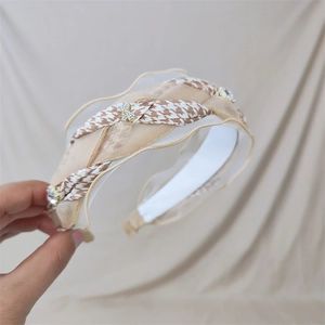 Detail of houndstooth headband featuring mesh ruffle trim and sparkling rhinestone bow