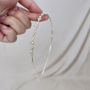 Detailed close-up of a gold metal headband with stars, moon, and pearls on silk