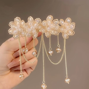 Detail of handmade beaded champagne flower hair clip with dangling gold fringe chains