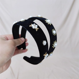 Détail du serre-tête en velours noir orné de perles blanches, feuilles d'or et strass
