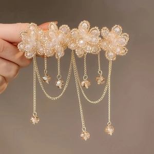 Detail of handmade beaded flower hair clip with champagne gold tassels and crystals