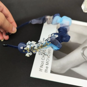 Close-up of blue organza headband with gold branch detailing and crystal beads