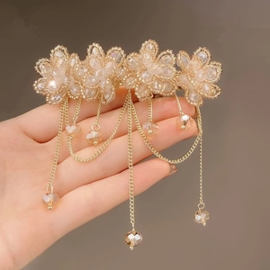 Detailed view of handcrafted flower hair clip with golden crystal tassels and beads