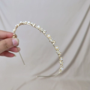 Détail macro d'un serre-tête doré avec fleurs sculptées, perles et strass brillants