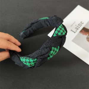 Detailed view of wide woven headband featuring green houndstooth and black pleated fabric