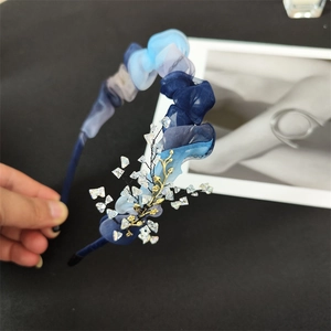 Close-up of blue pleated organza headband with gold branch and crystal beads detail