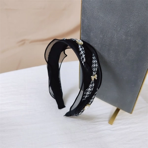 Detail of ruffled black headband featuring houndstooth ribbon and crystal heart charms