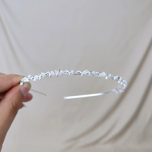 Close-up of thin silver metal headband with celestial stars, moons, and white pearls