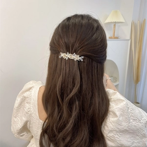 Rear view of a model wearing a flower crystal tassel hair clip with white pearls