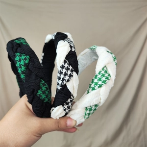 Detailed view of three plaid and solid fabric woven headbands in green, black, and white