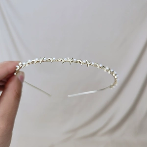 Detailed shot of gold metal headband with dainty star, moon and pearl embellishments