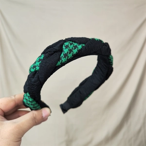 Close-up of a wide braided headband featuring green houndstooth and black fabric textures