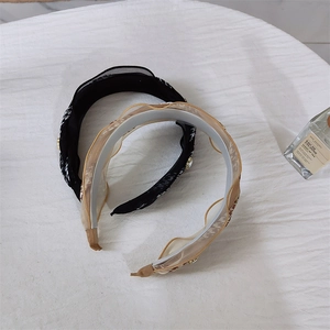 Detail of houndstooth weave and ruffled mesh textures on two elegant headbands