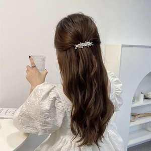 Detail of floral crystal hair clip with pearls worn on the back of a woman's head