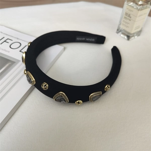 Detail of padded fabric headband featuring vintage gold metal studs and grey gemstones