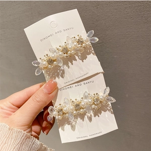 Detail view of crystal flower hair clips with pearls on a golden metal base