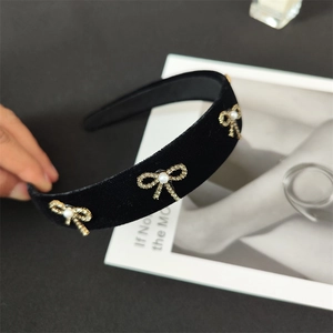 Detail of black velvet headband with three gold crystal bows and white center pearls