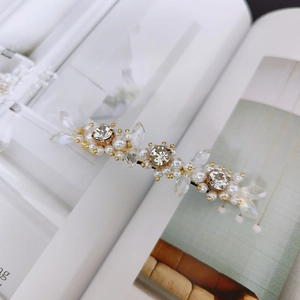 Macro detail of elegant flower hair clip with white pearls and clear crystals on gold metal