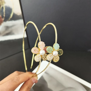 Detailansicht von Haarreifen mit Perlenblumen und Strass auf goldfarbenem Metallreif