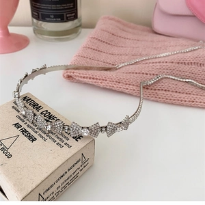 Detail of silver thin headband featuring sparkling rhinestones in delicate bow designs