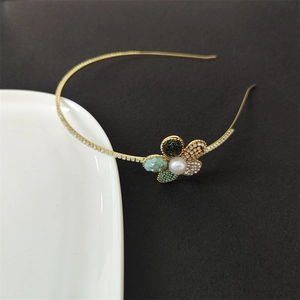 Nahaufnahme eines goldenen Blumen Stirnband mit Perlen und Kristallen auf dunklem Grund