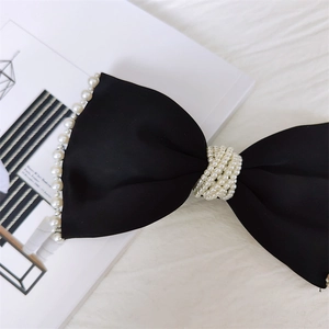 Dettaglio del fermaglio per capelli in raso nero con decorazioni di perle bianche eleganti