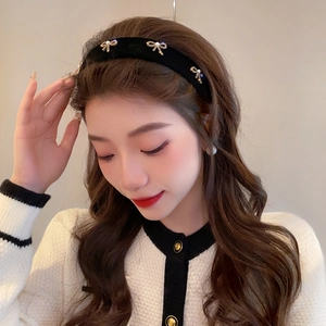 Detail of vintage black velvet headband with three golden bows and pearls for women