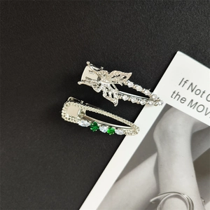 Detail of emerald green and white rhinestone hair clips with a silver butterfly motif