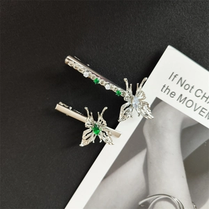 Detailed macro view of butterfly hair clips with emerald green and white zircons