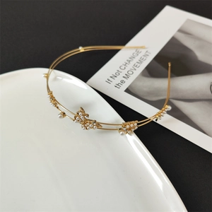 Detailed view of a gold double-layer headband with rhinestone butterflies and pearls
