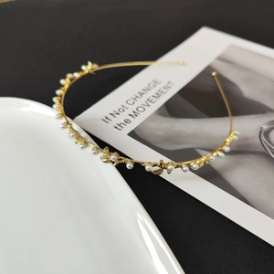 Detail of slim gold headband featuring small white pearls and metallic gold leaves