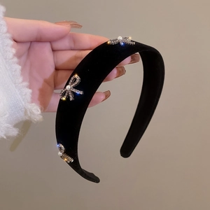 Close-up of black velvet headband featuring sparkling rhinestone bow and pearl details
