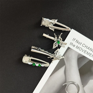 Detailed set of silver butterfly hair clips with emerald green and clear gemstones