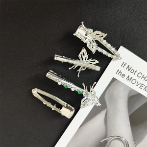 Detailed view of silver butterfly hair clip set with emerald green and white zircons