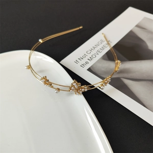 Detailed view of golden double-layer headband with rhinestones and pearl butterfly ornaments