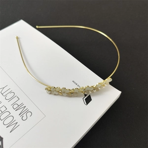 Close-up of golden headband with cat eye stone butterfly and white floral accents